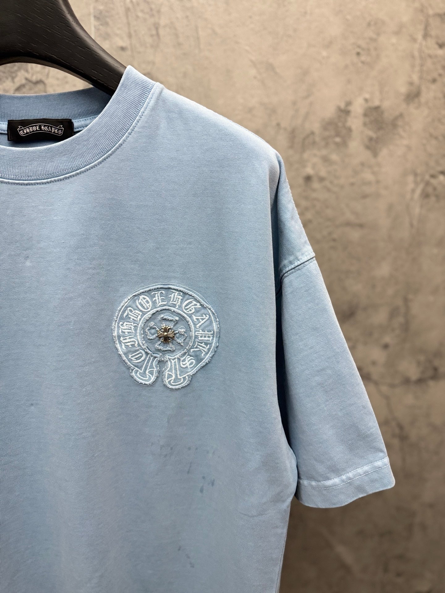 Light blue T-shirt side view with round chest crest embroidery