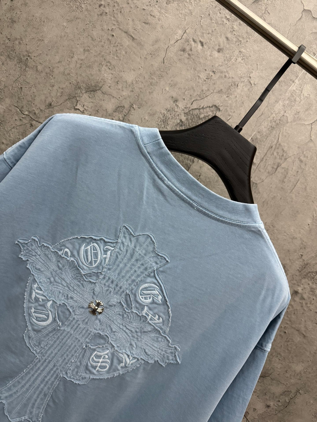 Light blue T-shirt close-up of back crest embroidery with small gold detail