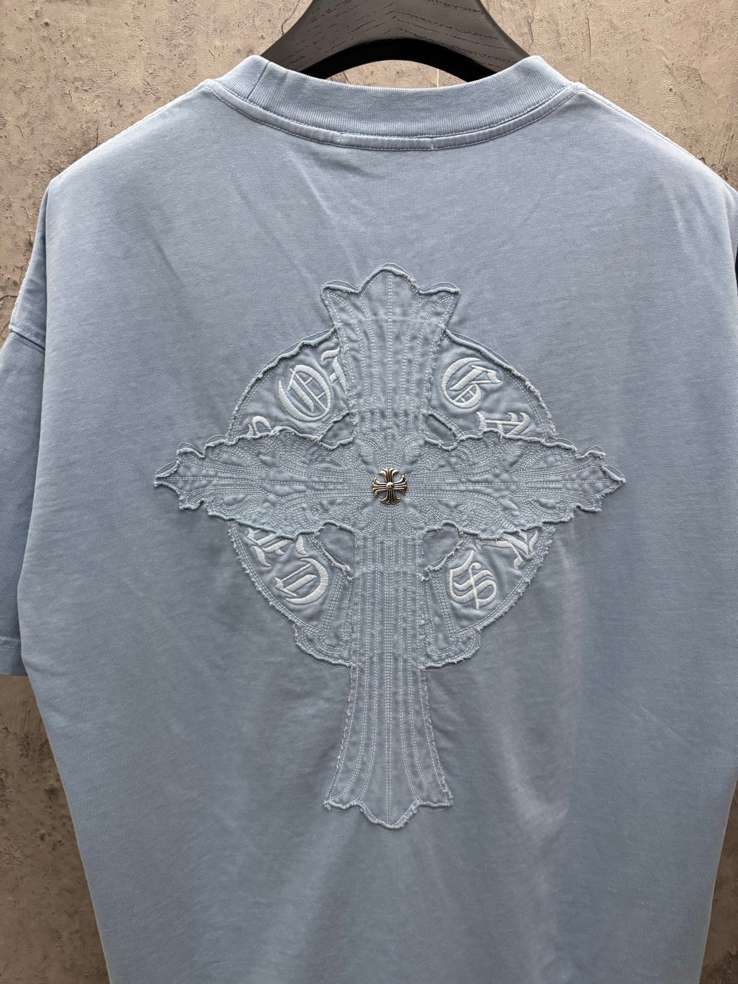 Light blue T-shirt back view with large cross-shaped crest embroidery