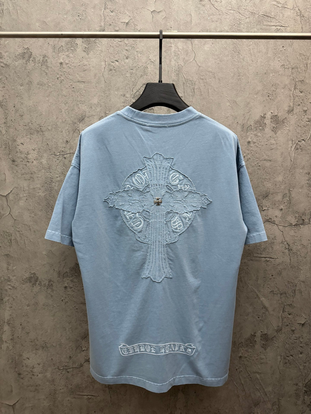 Light blue T-shirt, back view, with large crest graphic and decorative emblem