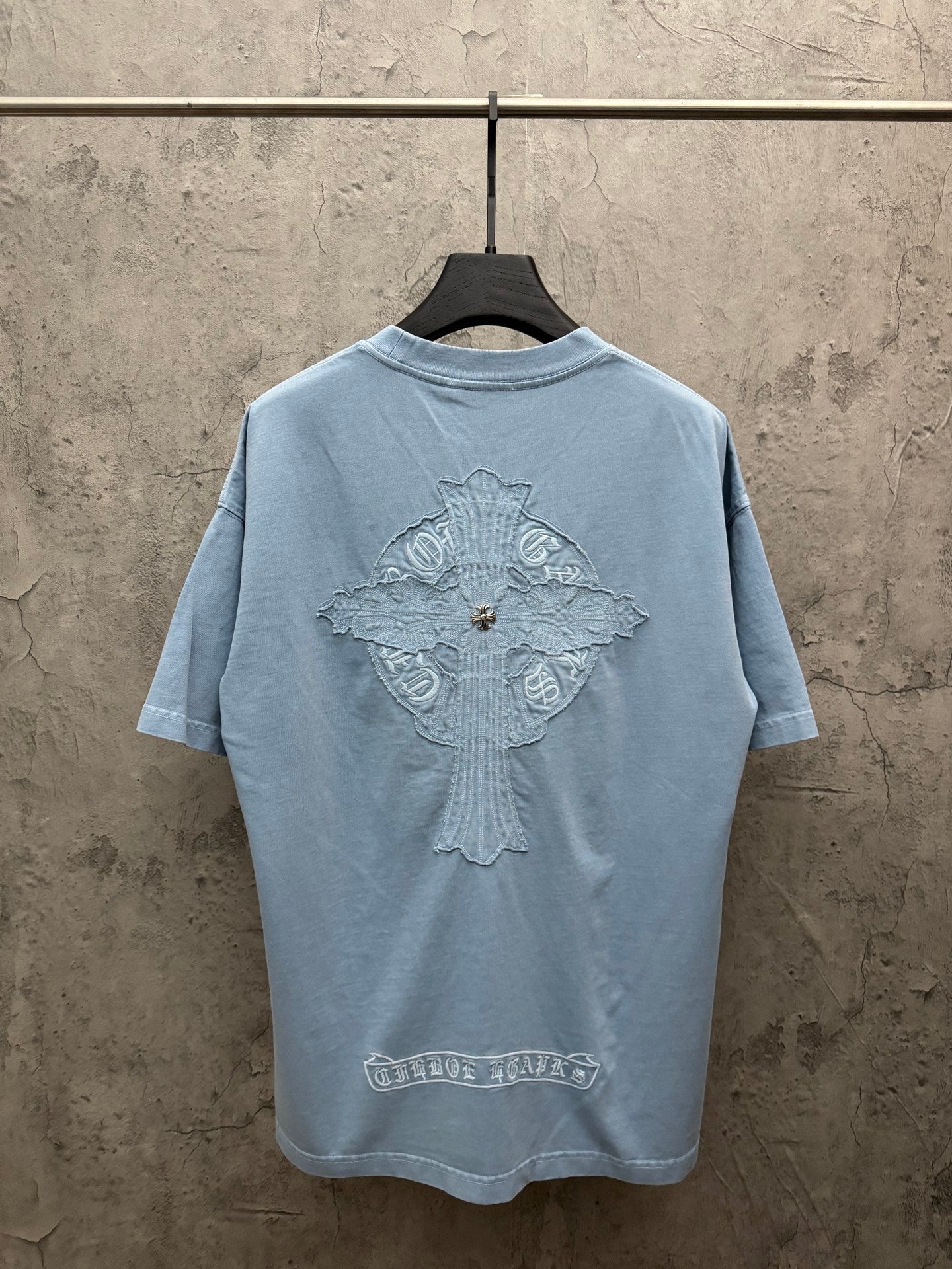 Light blue T-shirt, back view, with large crest graphic and decorative emblem