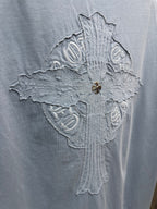 Close-up of large crest embroidery on light blue T-shirt back, with gold pin