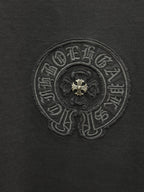 Dark gray T-shirt close-up of embroidered circular crest with fleur-de-lis