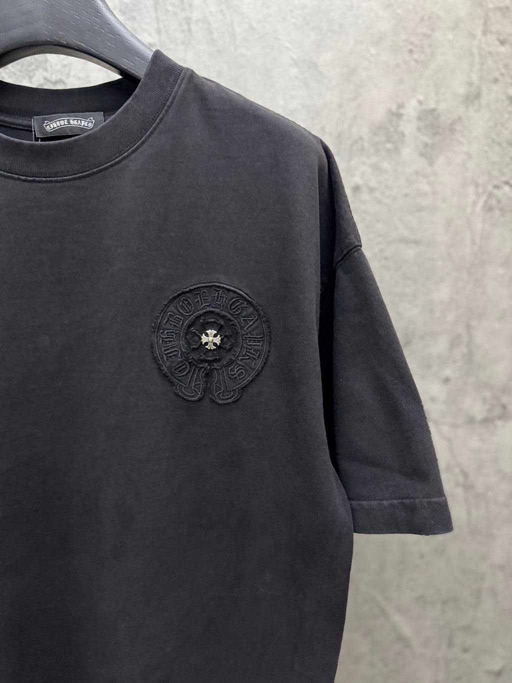 Dark crewneck short-sleeve T-shirt with raised chest emblem in a circular frame