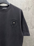 Dark crewneck short-sleeve T-shirt with raised chest emblem in a circular frame