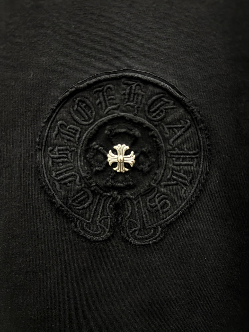 Close-up of embroidered circular emblem on dark T-shirt front
