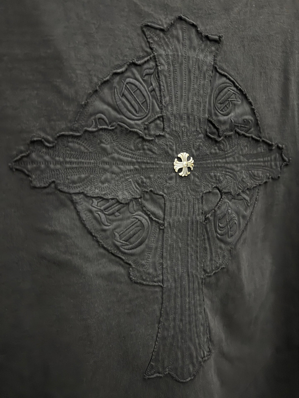Close-up of embroidered cross graphic on dark T-shirt back