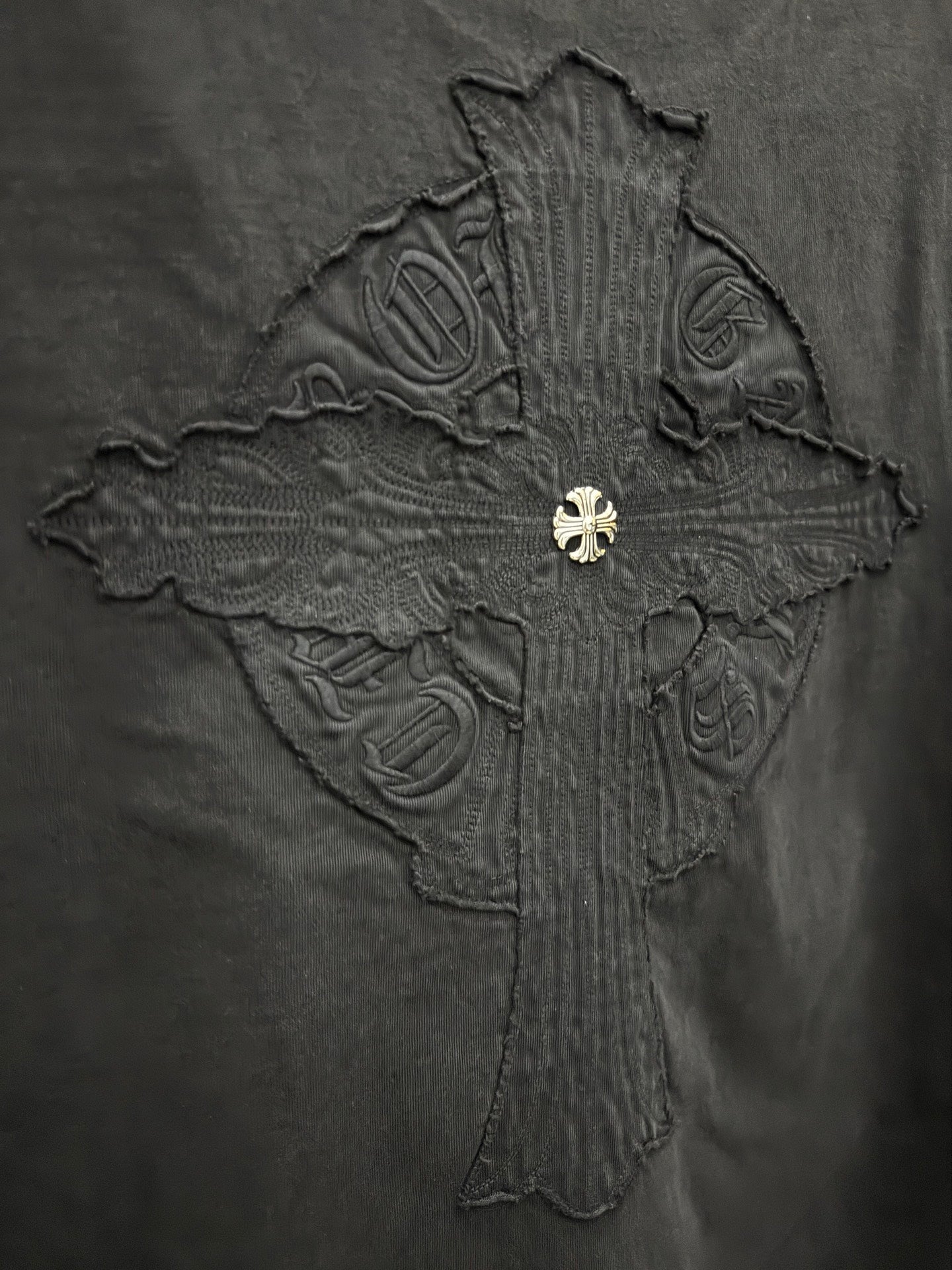 Close-up of embroidered cross graphic on dark T-shirt back