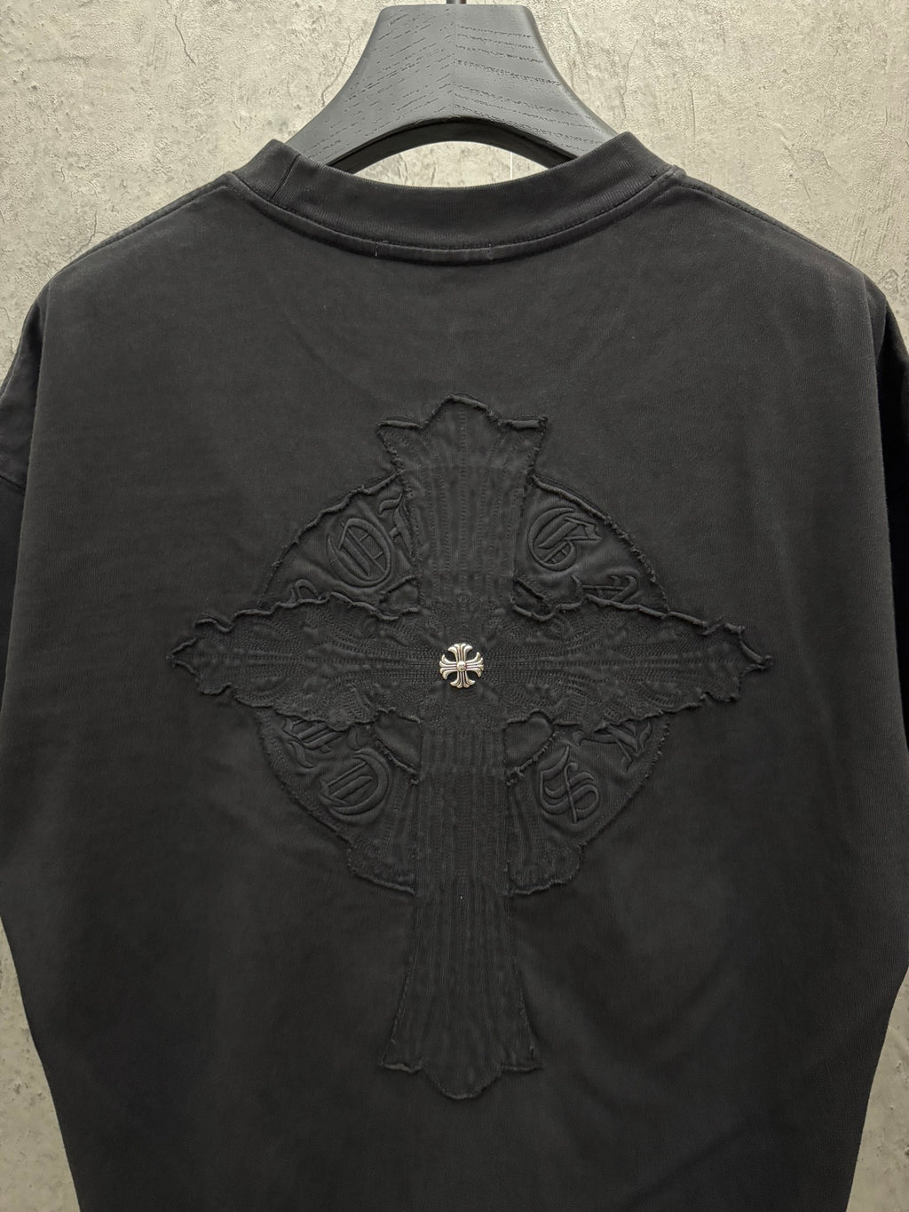 Back view of dark crewneck short-sleeve T-shirt with central embroidered cross