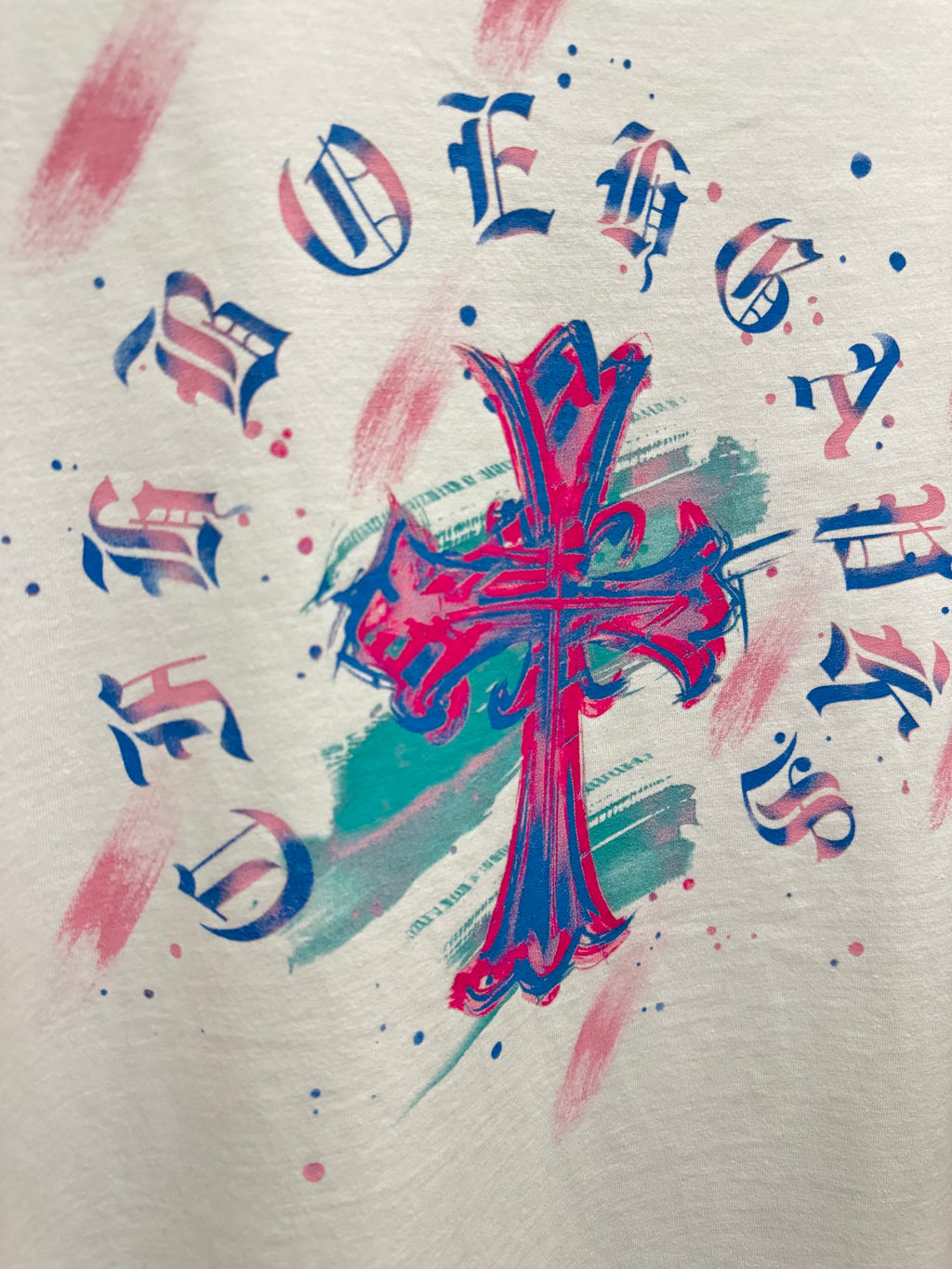 White T-shirt close-up of colorful cross graphic with note symbols