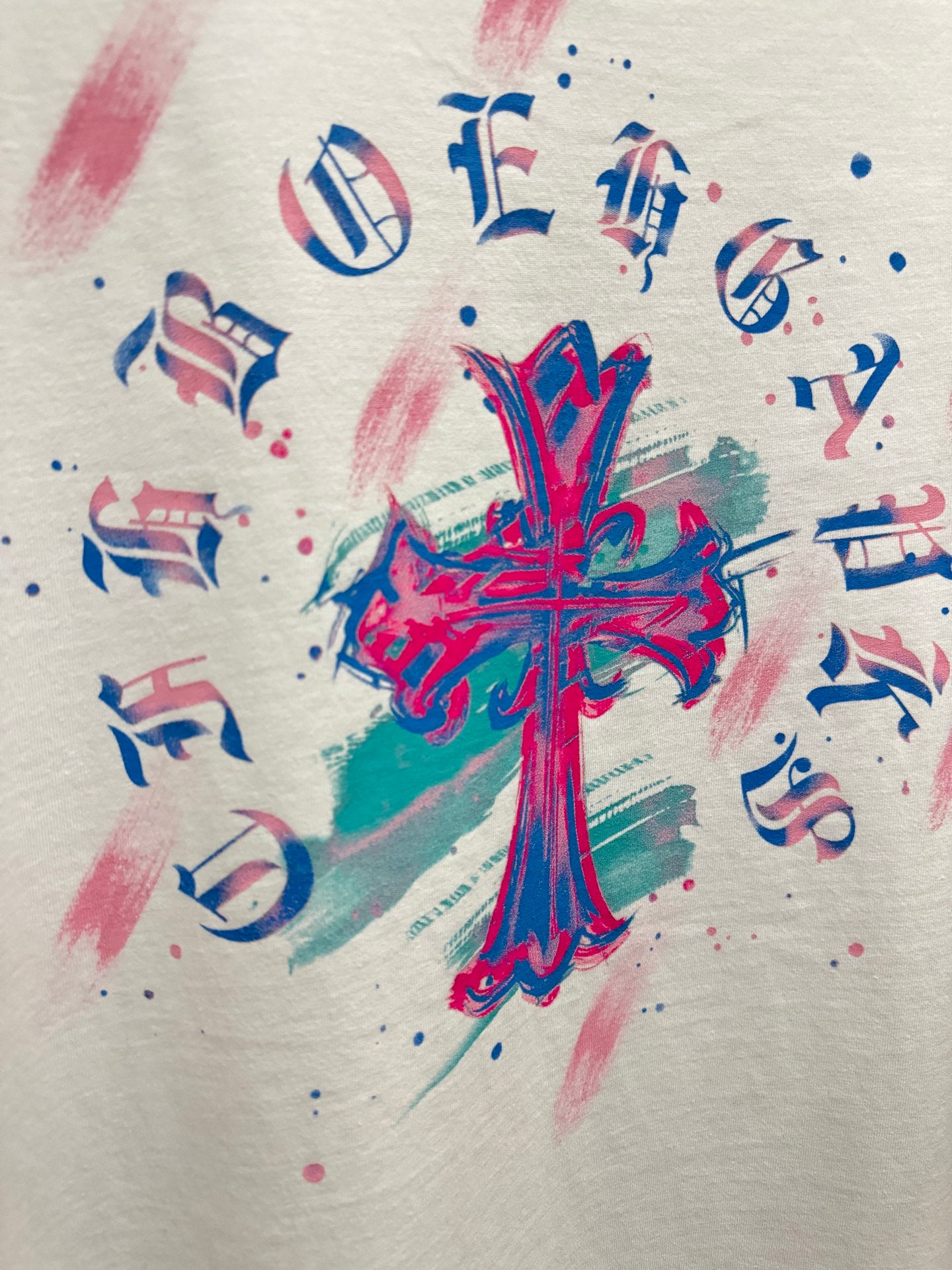 White T-shirt close-up of colorful cross graphic with note symbols