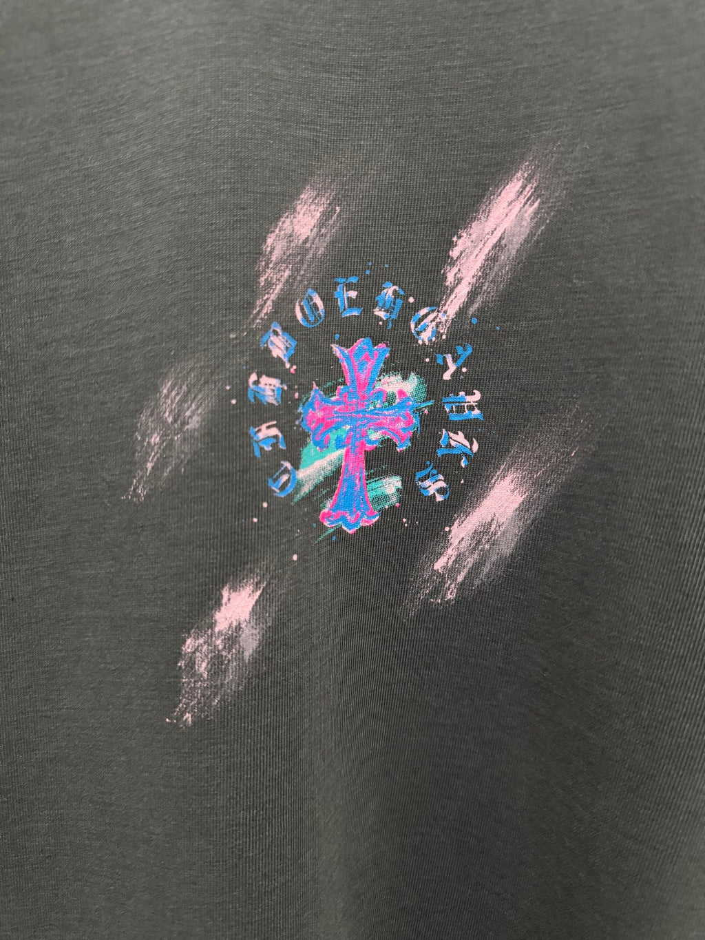 Dark gray T-shirt close-up of colorful cross graphic print with paint-splash style