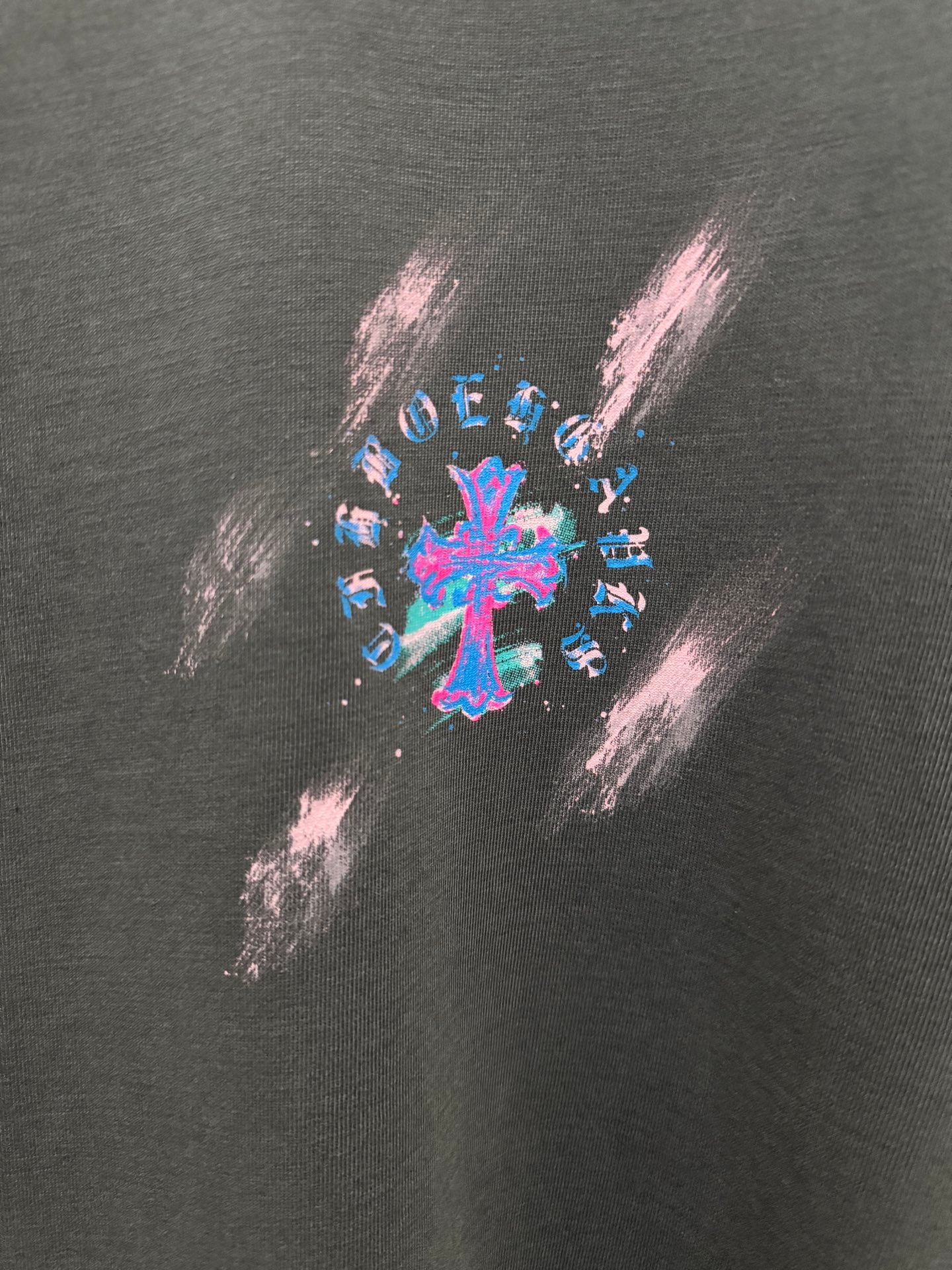 Dark gray T-shirt close-up of colorful cross graphic print with paint-splash style