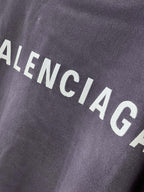 BALENCIAGA logo text on dark purple T-shirt fabric, close-up
