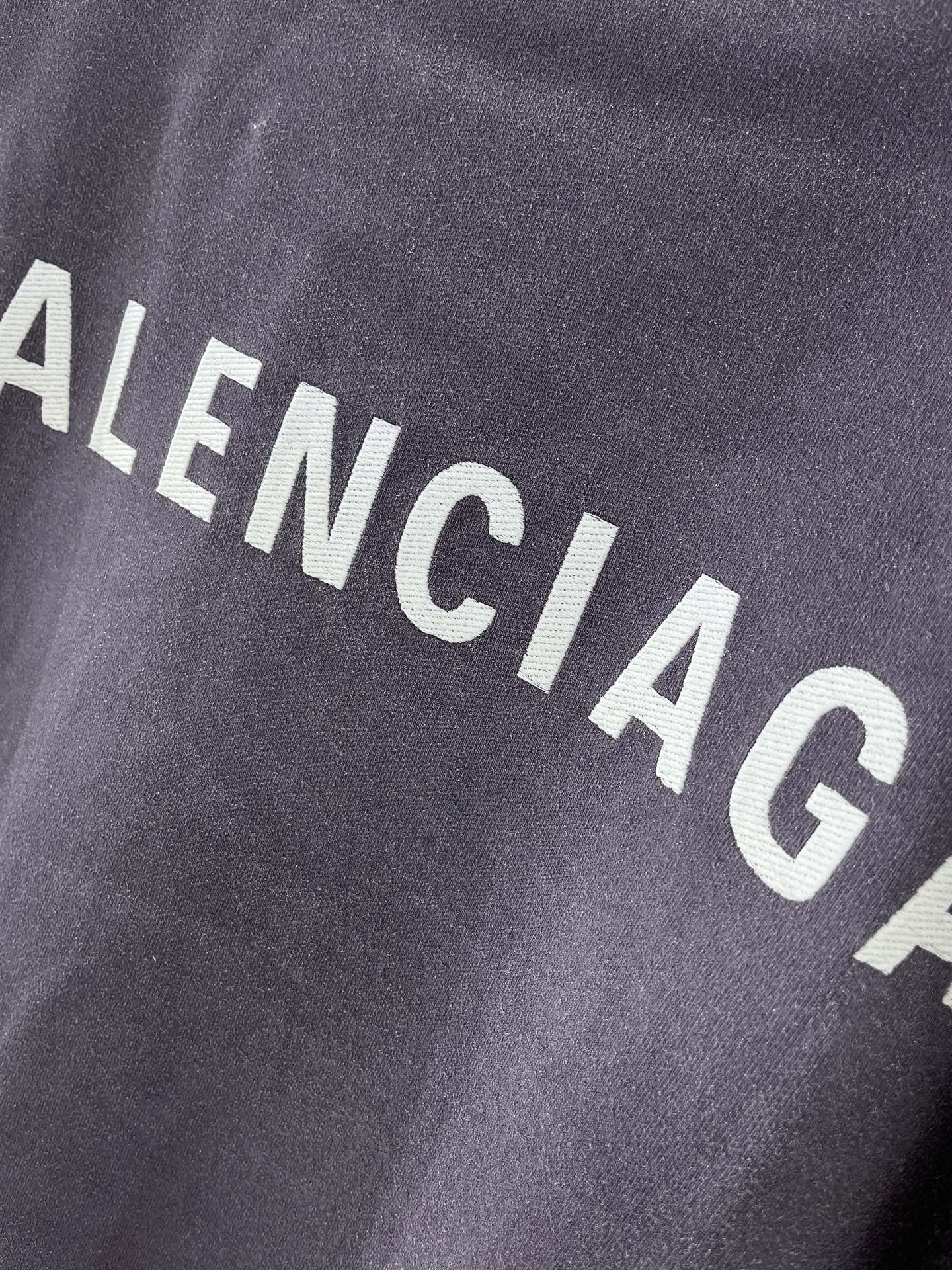 BALENCIAGA logo text on dark purple T-shirt fabric, close-up