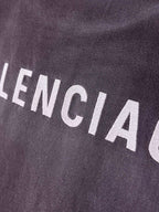BALENCIAGA logo text on dark purple T-shirt fabric, close-up