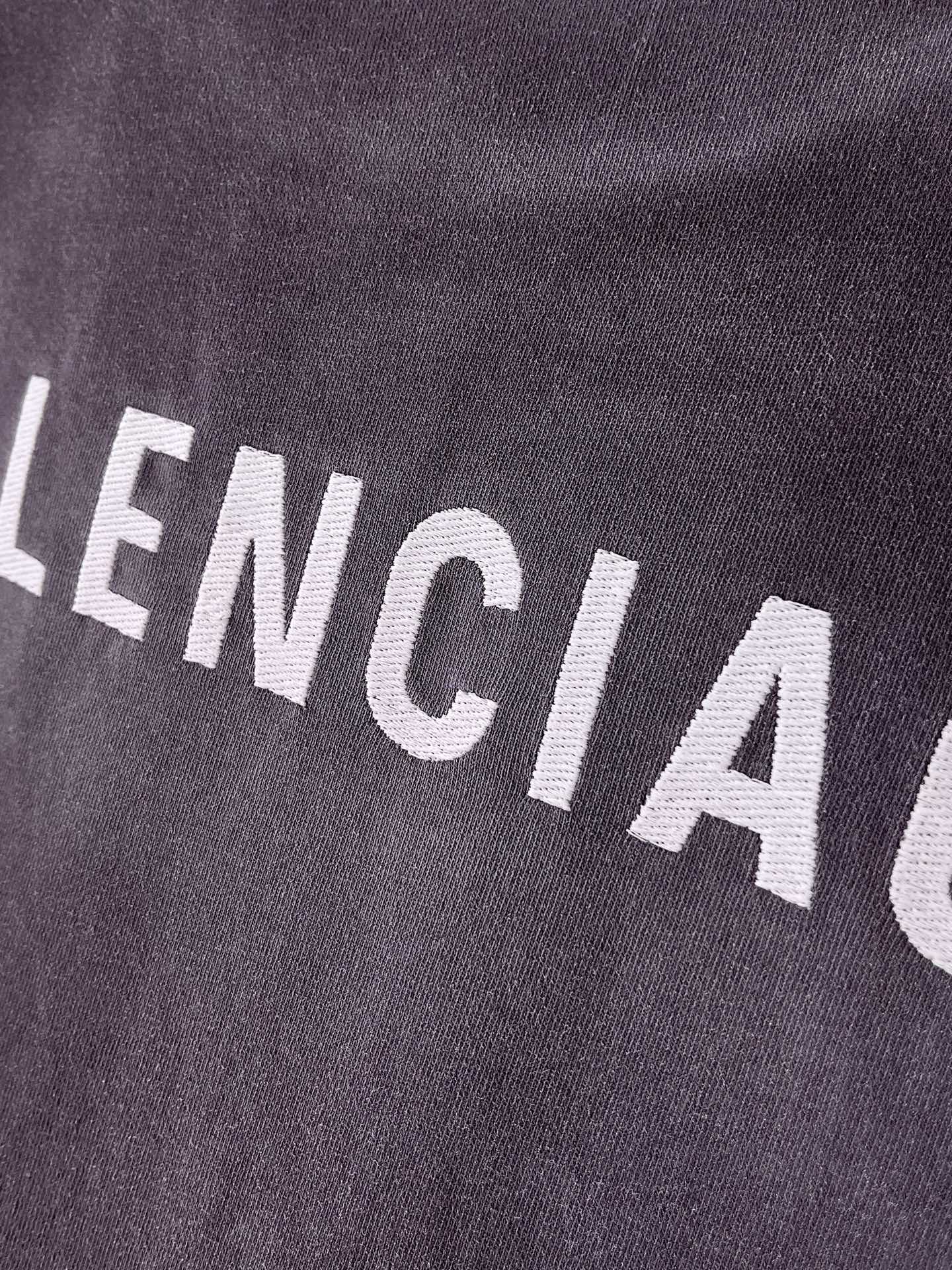 BALENCIAGA logo text on dark purple T-shirt fabric, close-up