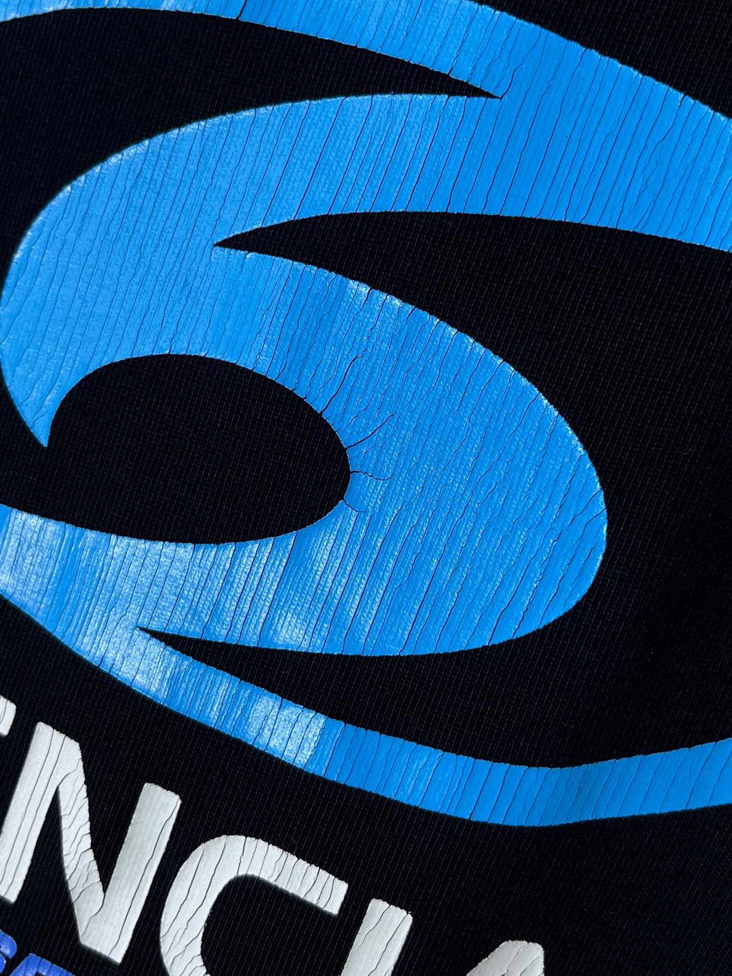 Black Balenciaga T-shirt close-up of blue swirl logo detail