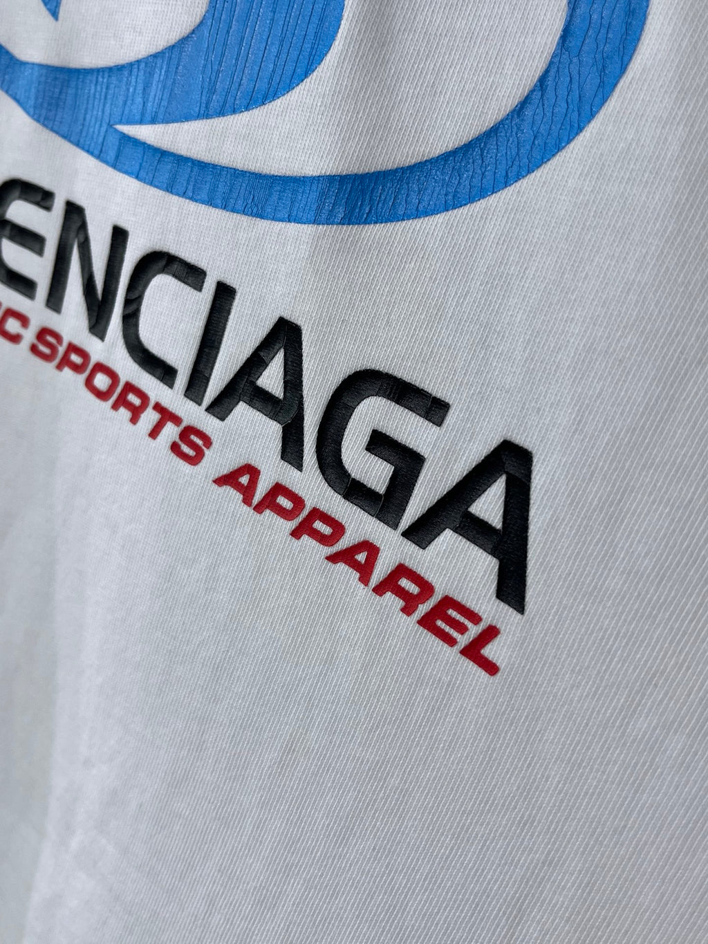 Balenciaga white T-shirt close-up of black “BALENCIAGA” and red “Authentic sports apparel”