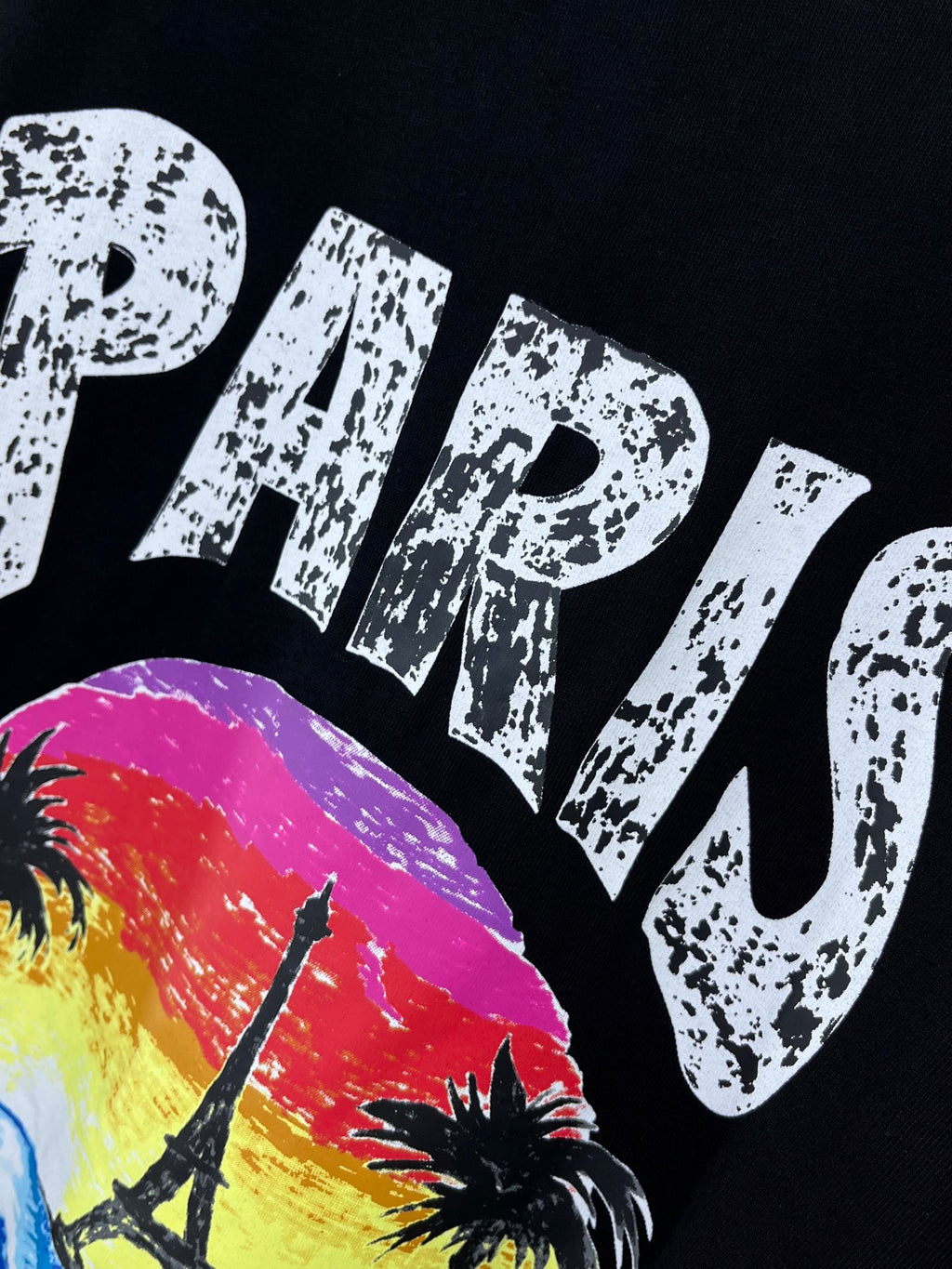 Black T-shirt close-up of PARIS lettering over a multicolor scene