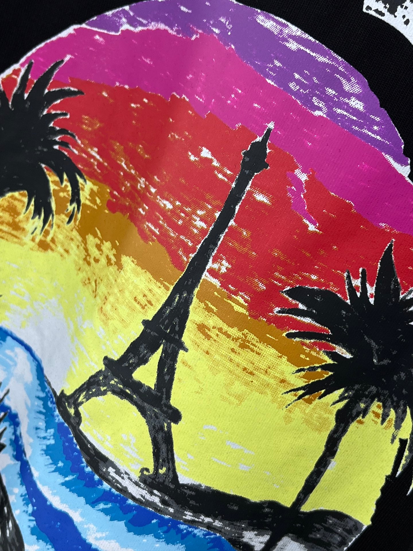 Black T-shirt close-up: Eiffel Tower and palm trees on a colorful graphic