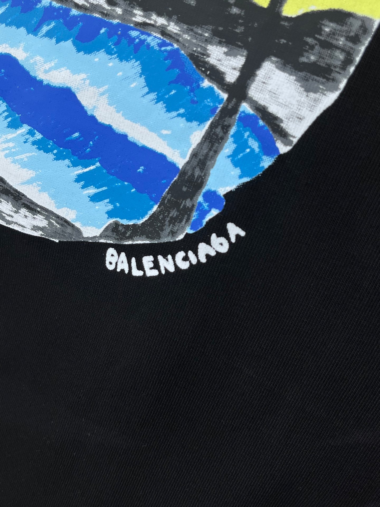 Black T-shirt with BALENCIAGA logo text beneath a blue and white wave graphic