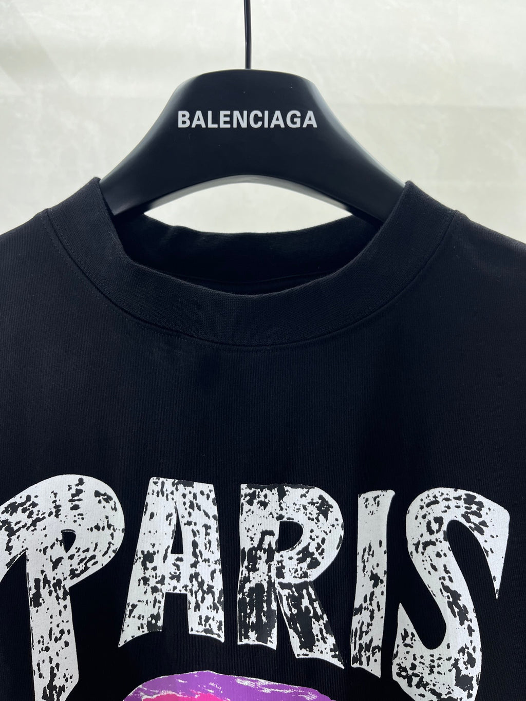 Black T-shirt crew neckline with collar seam, hanging on a black hanger