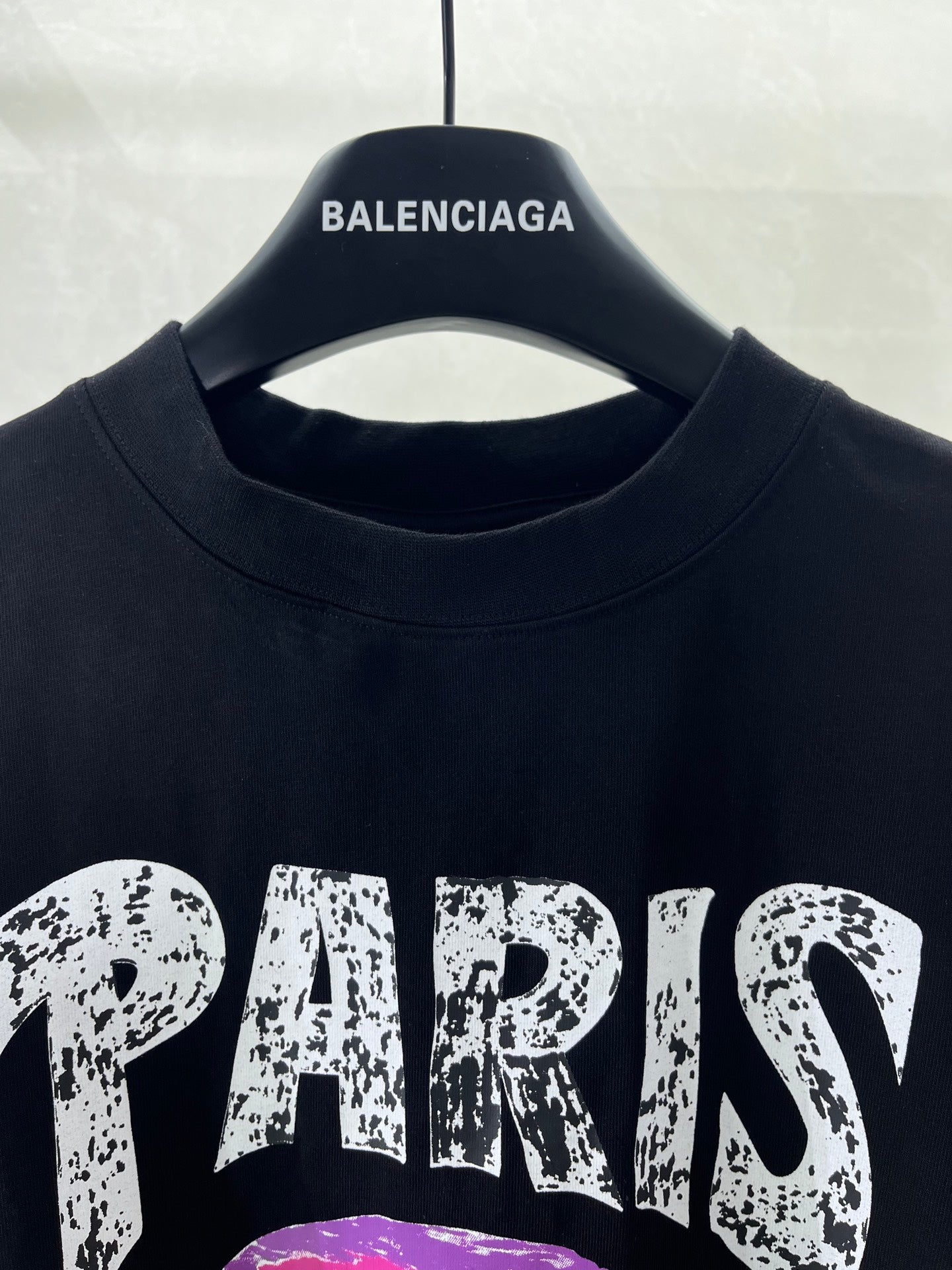 Black T-shirt crew neckline with collar seam, hanging on a black hanger