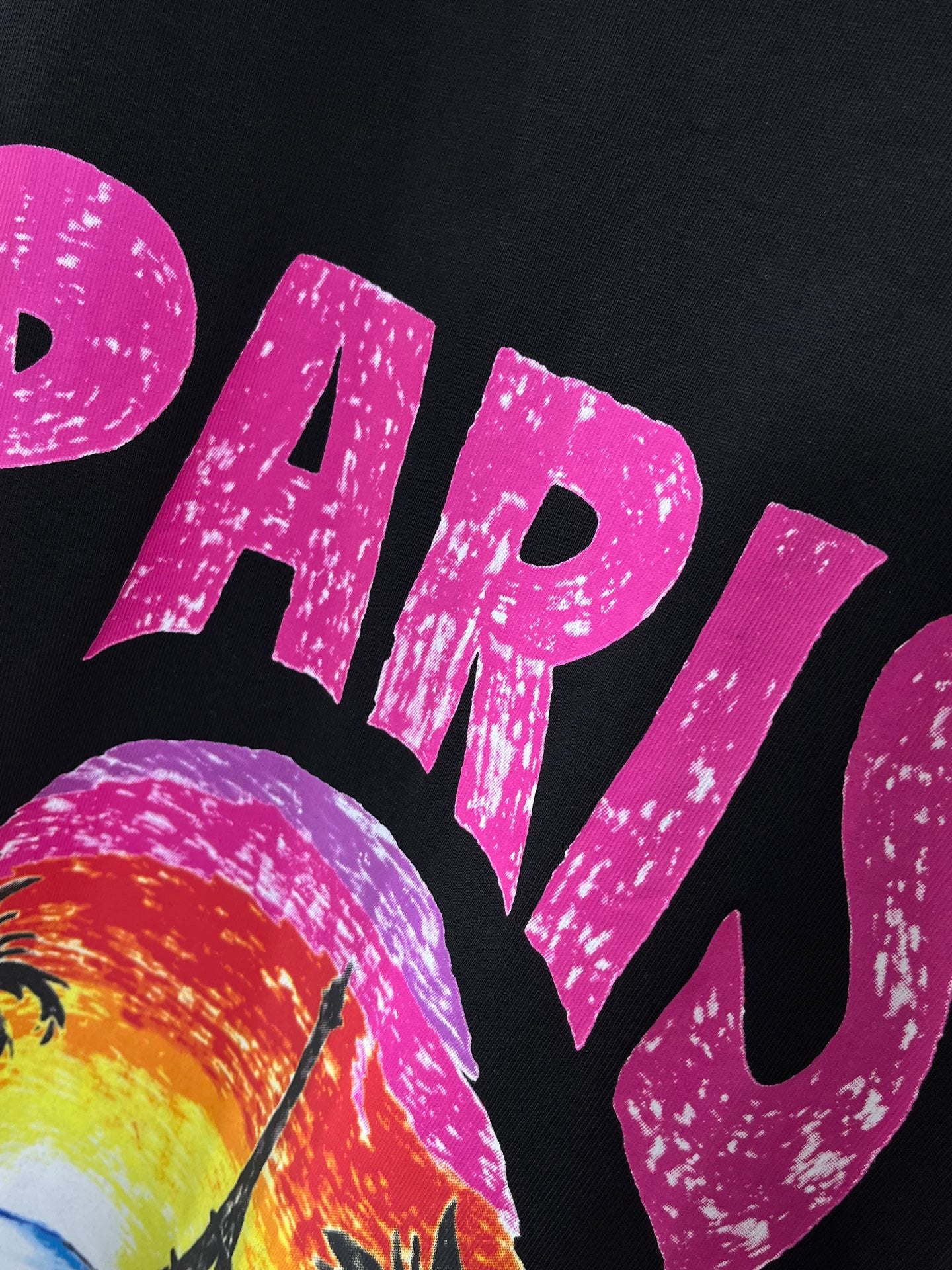Balenciaga black T-shirt close-up of large pink PARIS lettering and beach scene