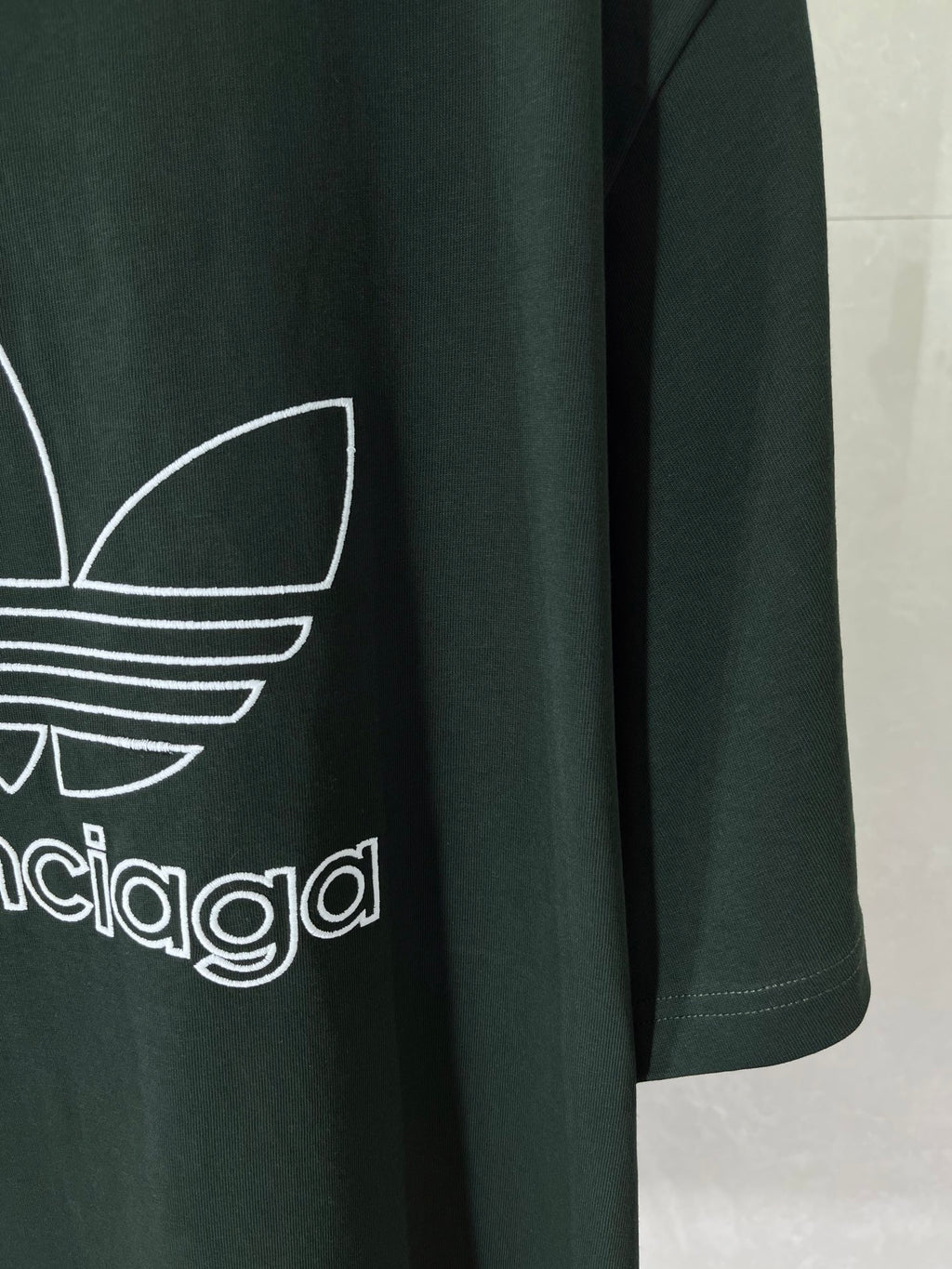 Dark green T-shirt front detail with white adidas trefoil and wordmark print