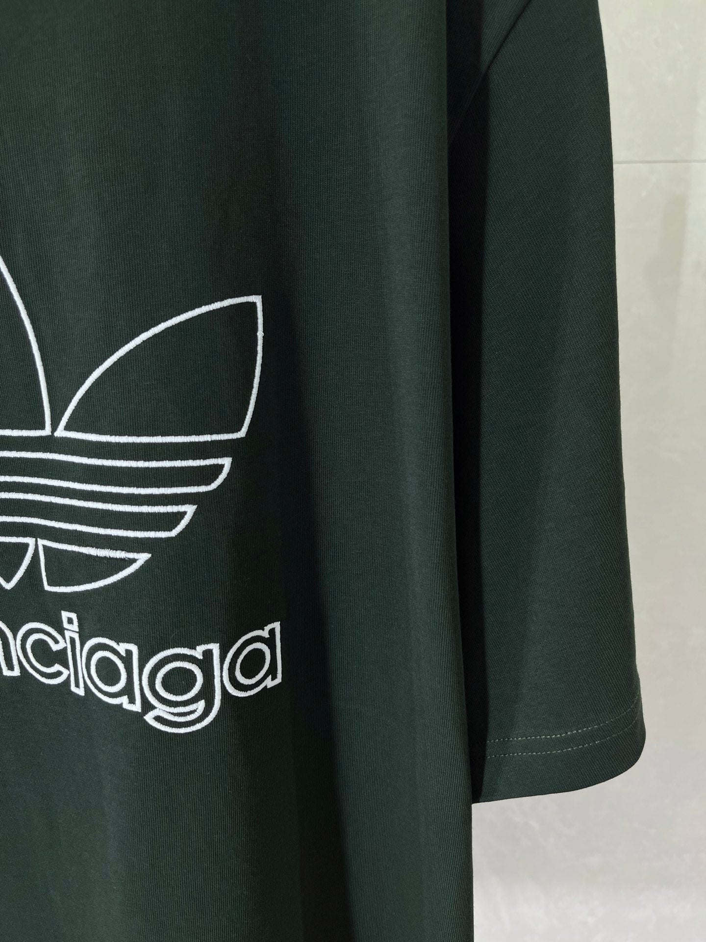 Dark green T-shirt front detail with white adidas trefoil and wordmark print
