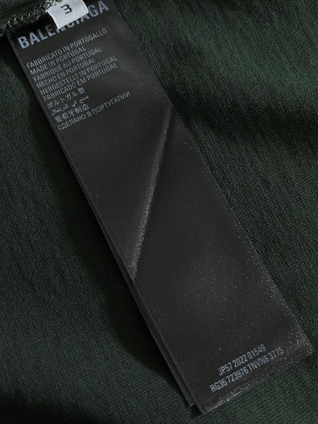 Dark green T-shirt with black fabric care label tag on inner seam
