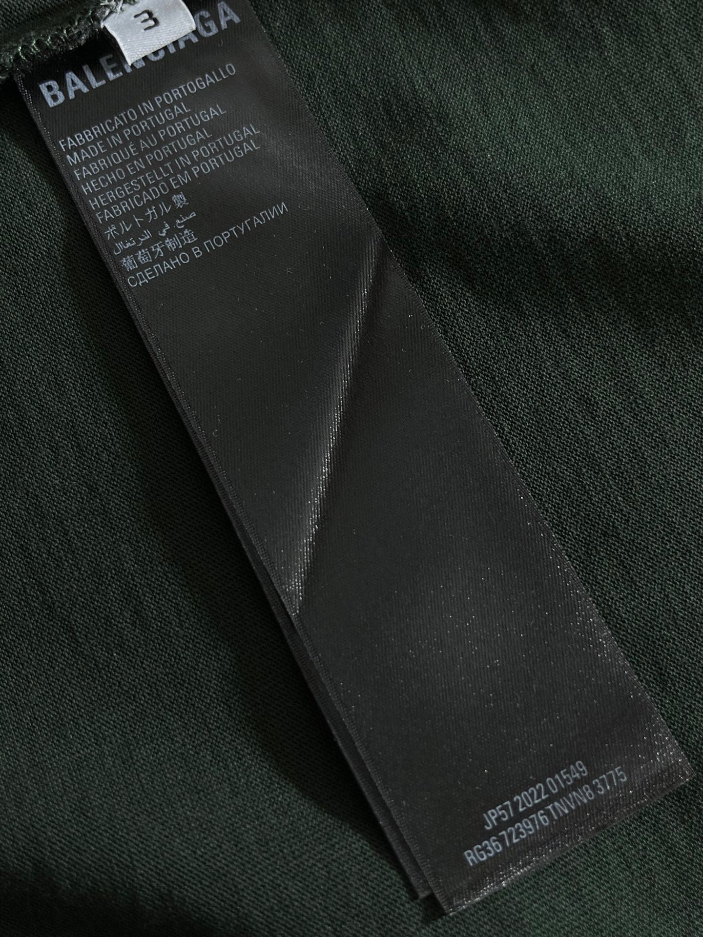 Dark green T-shirt with black fabric care label tag on inner seam