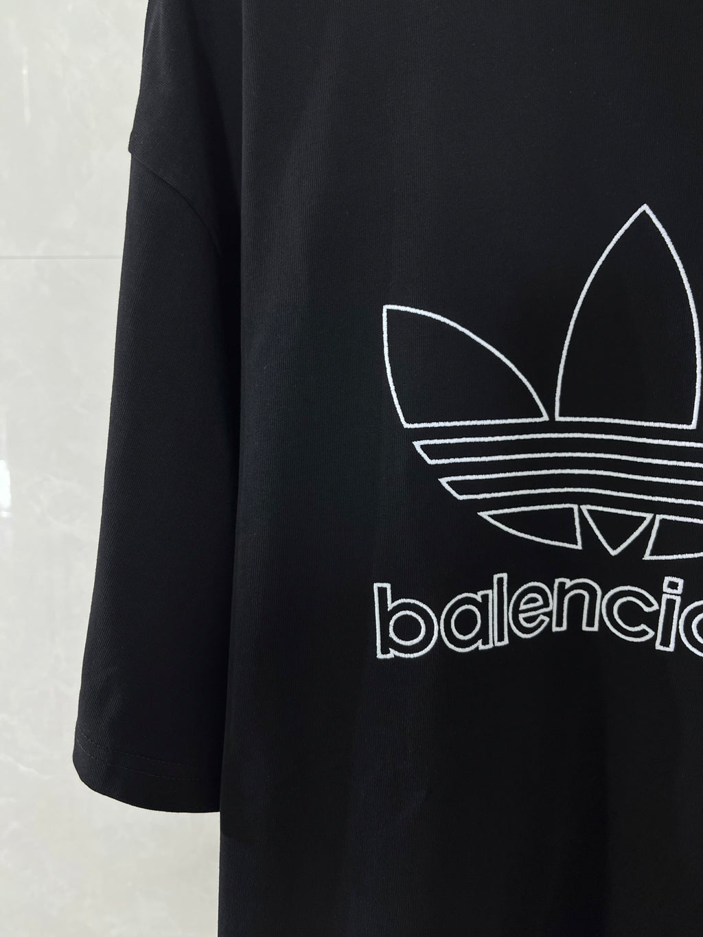 Balenciaga T-shirt with large white trefoil graphic and partial logo text on dark