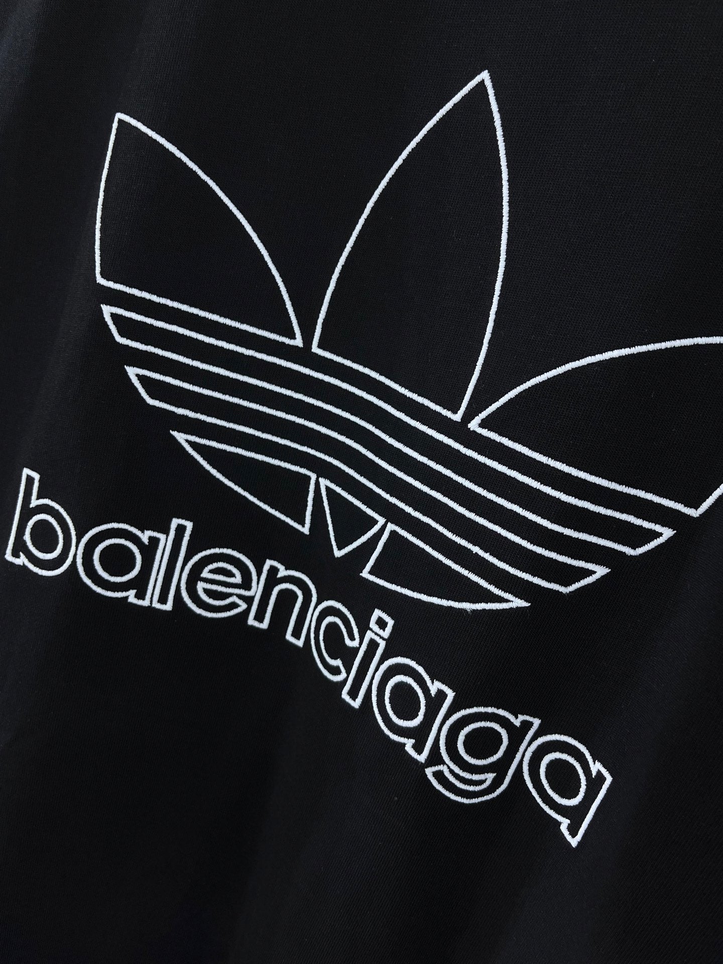 Balenciaga T-shirt front with white trefoil graphic and balenciaga lettering on dark