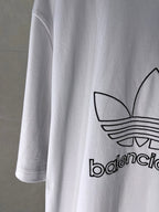 White Balenciaga logo T-shirt, side close-up of trefoil emblem and printed text.