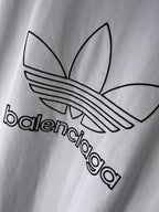 White Balenciaga logo T-shirt, detailed view of trefoil graphic and “balenciaga” text.