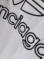 White Balenciaga logo T-shirt, close-up of “balenciaga” lettering with outline design.