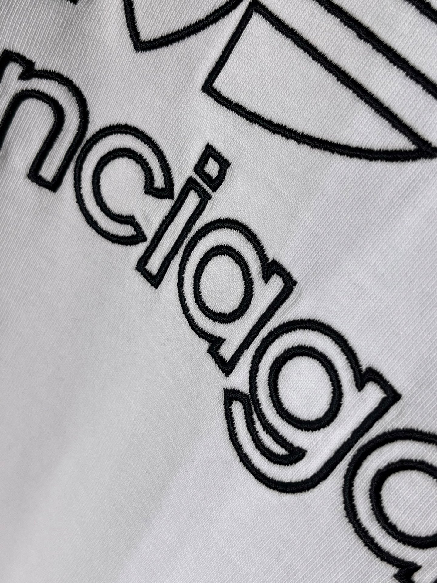 White Balenciaga logo T-shirt, close-up of “balenciaga” lettering with outline design.