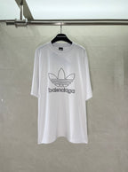White Balenciaga graphic logo T-shirt with large trefoil-style emblem on chest.
