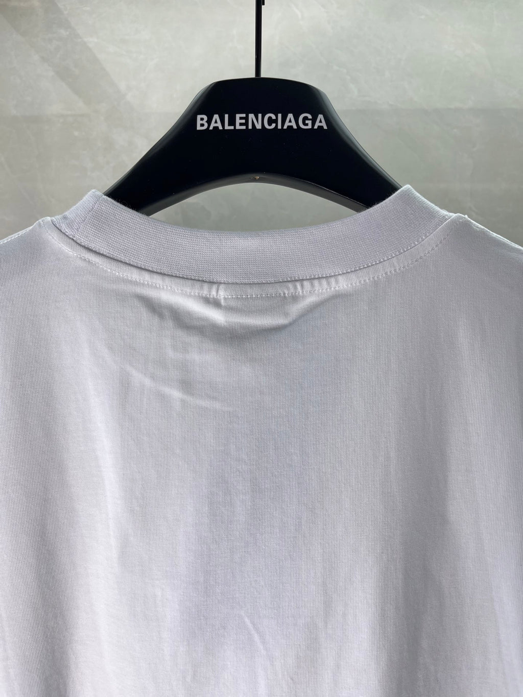 White Balenciaga logo T-shirt, close-up of crew neck and hanging collar view.