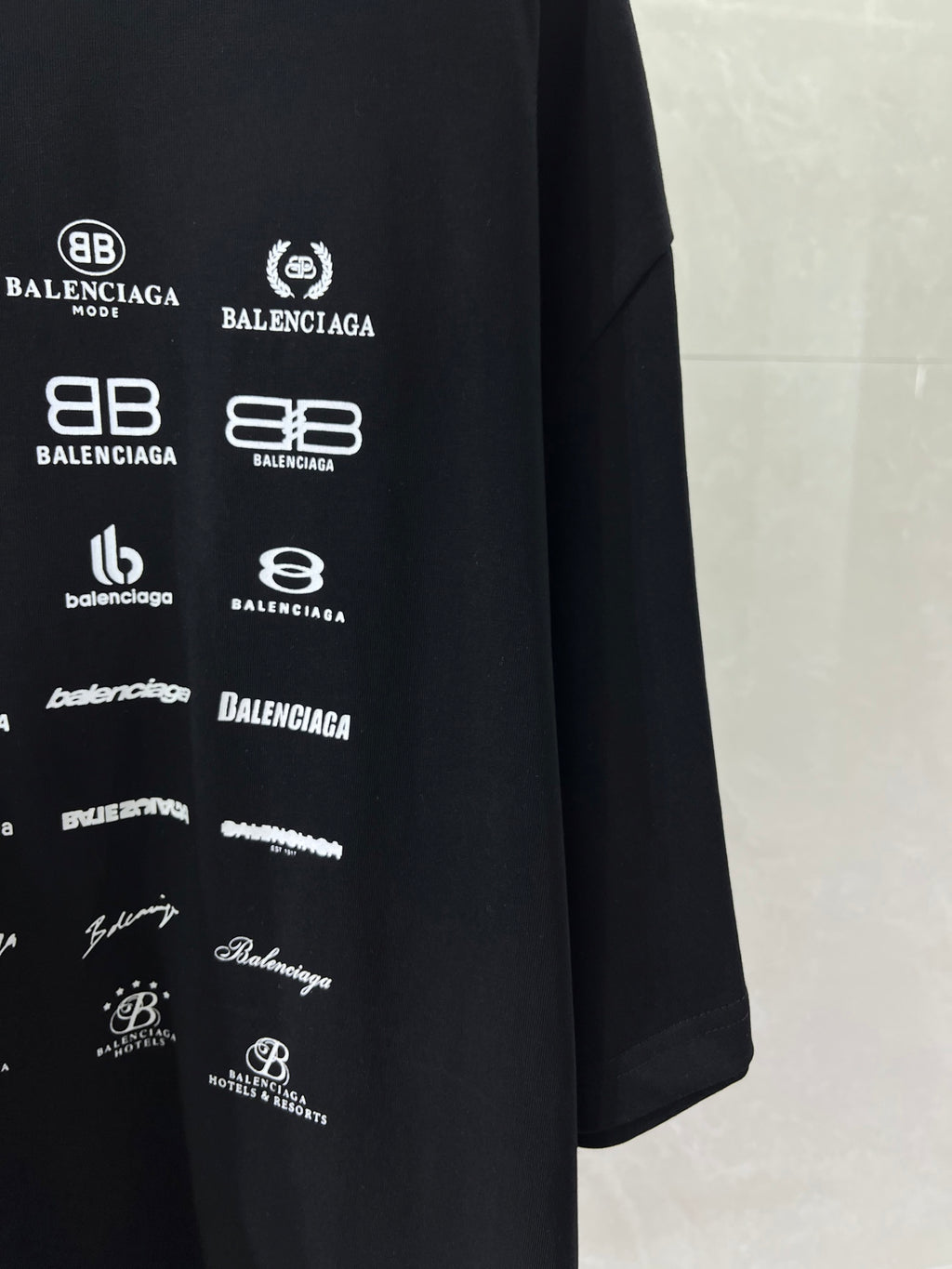 Dark T-shirt with repeating Balenciaga logo prints, close-up