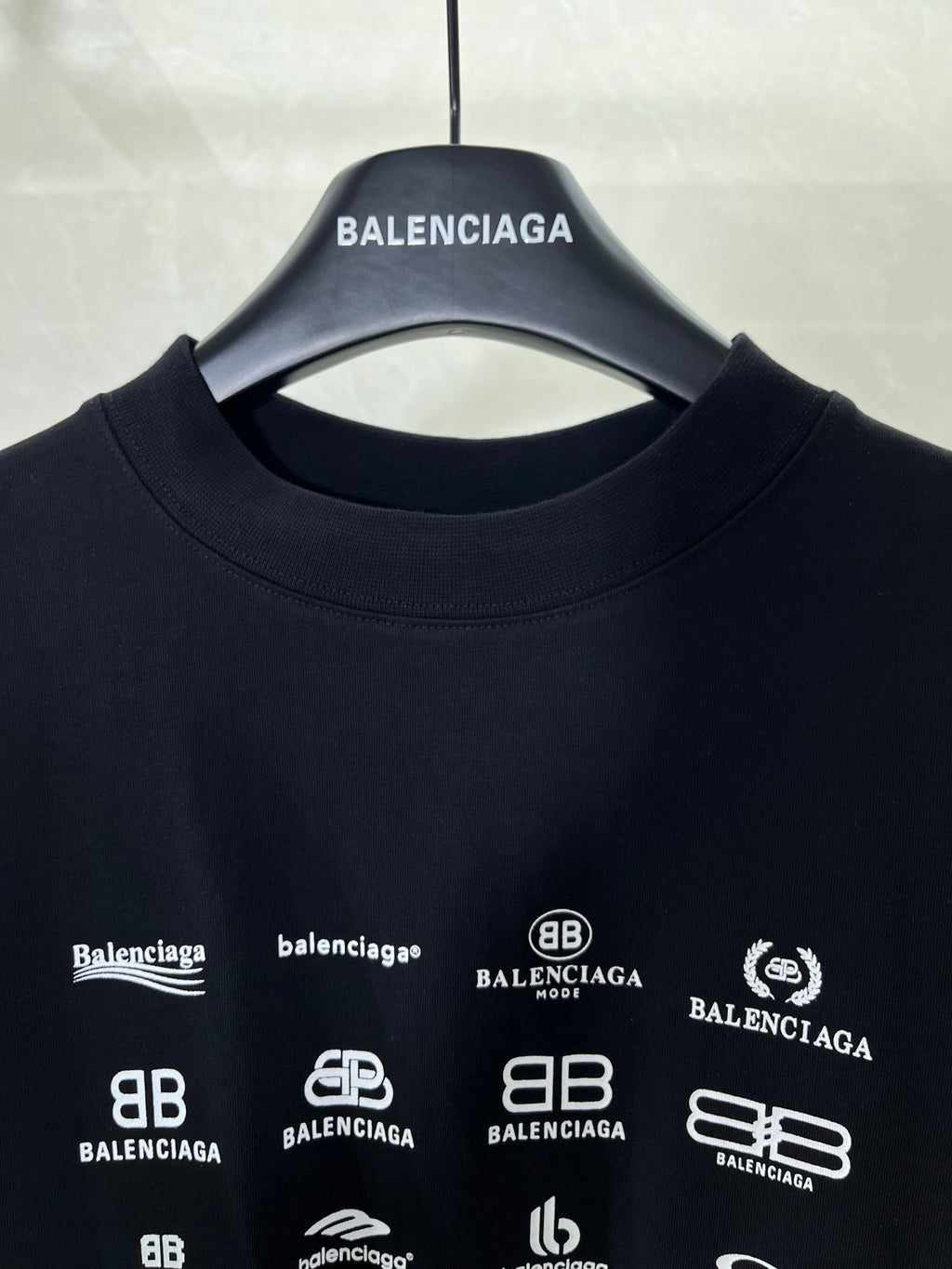 Dark crew-neck T-shirt neckline with Balenciaga hanger and logo print close-up