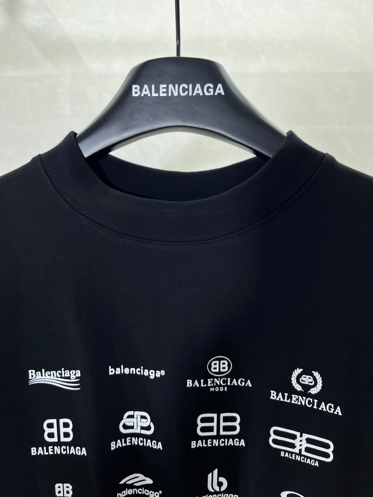 Dark crew-neck T-shirt neckline with Balenciaga hanger and logo print close-up