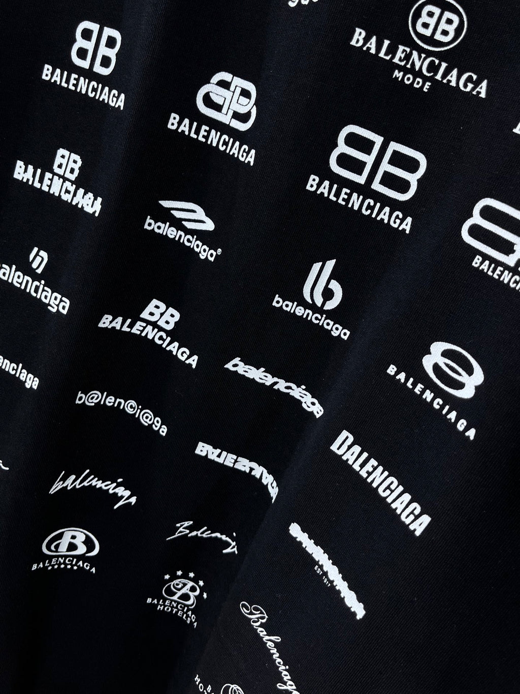 Dark T-shirt fabric close-up with white Balenciaga logo pattern