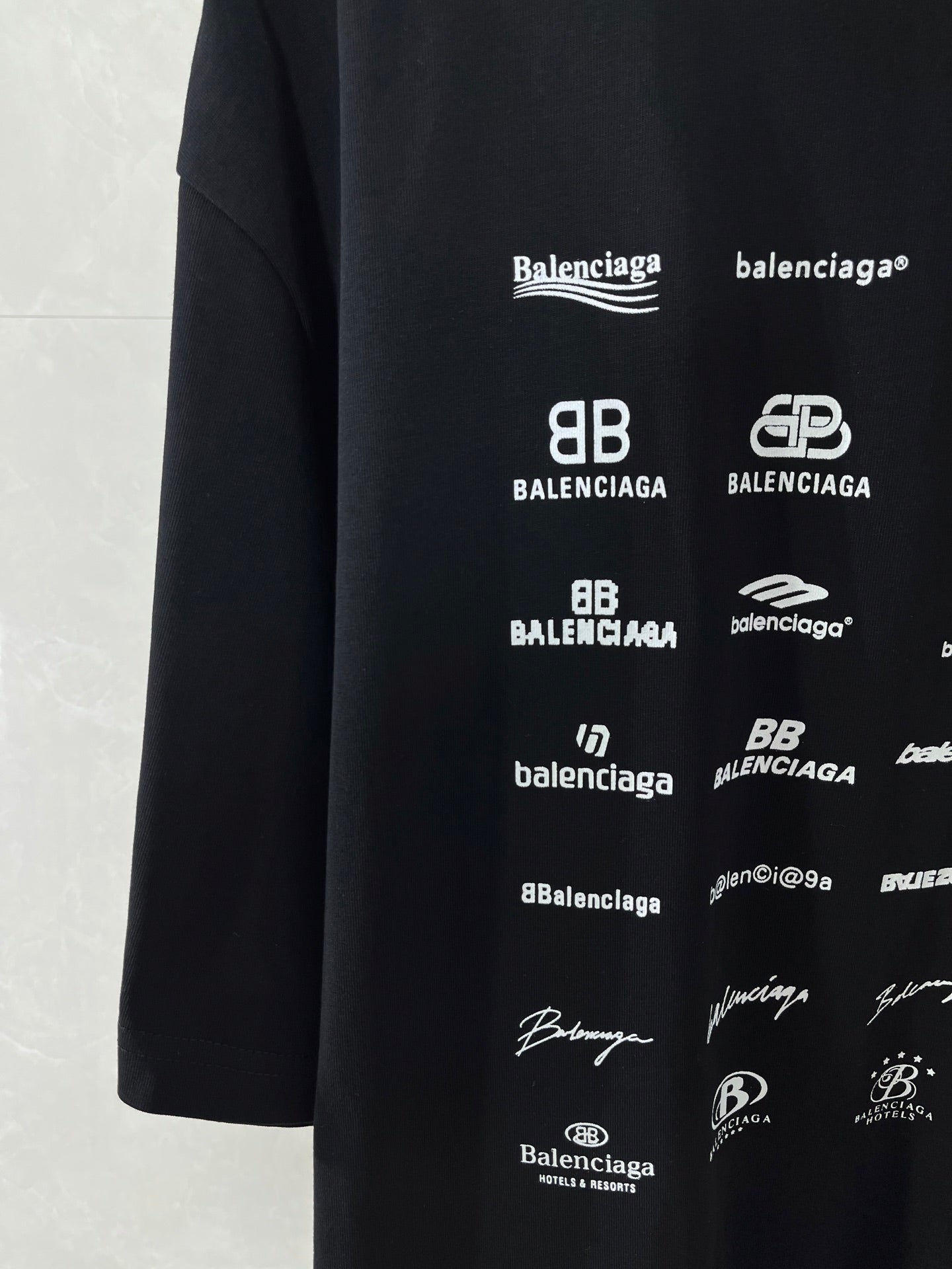 Dark T-shirt side with repeating Balenciaga logo prints