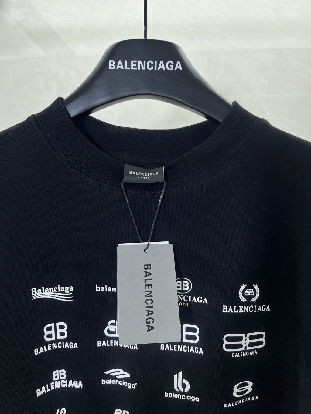 Dark crew-neck T-shirt with white Balenciaga logo print and hanging tag