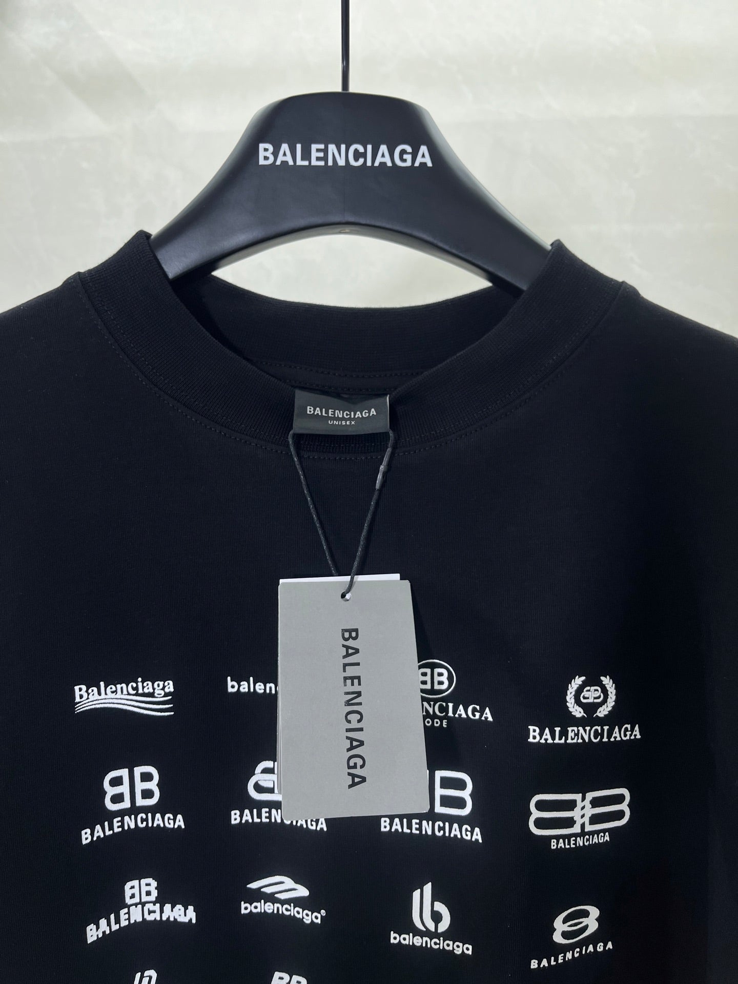 Dark crew-neck T-shirt with white Balenciaga logo print and hanging tag