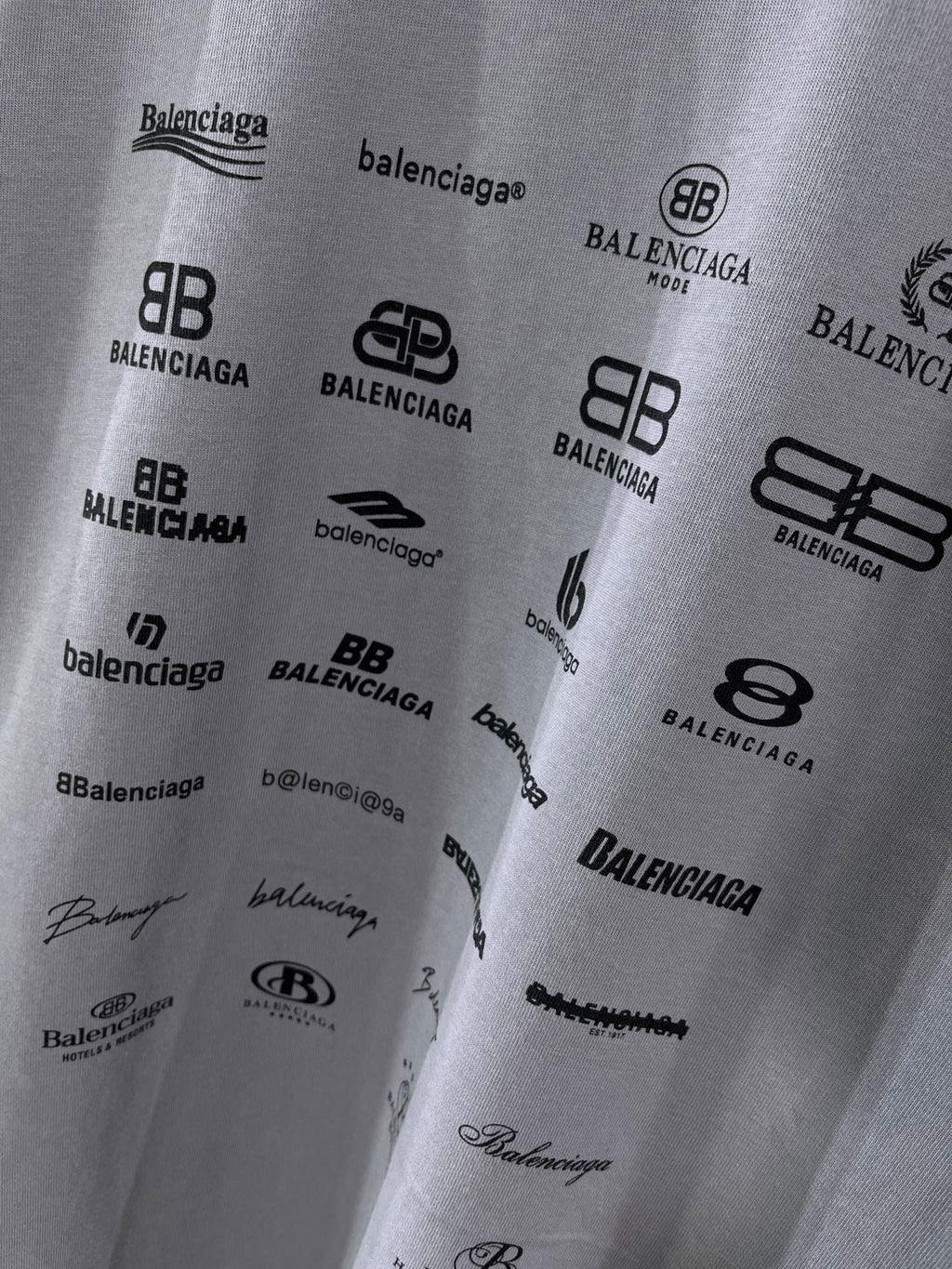 Balenciaga T-shirt fabric close-up showing multiple black logo prints