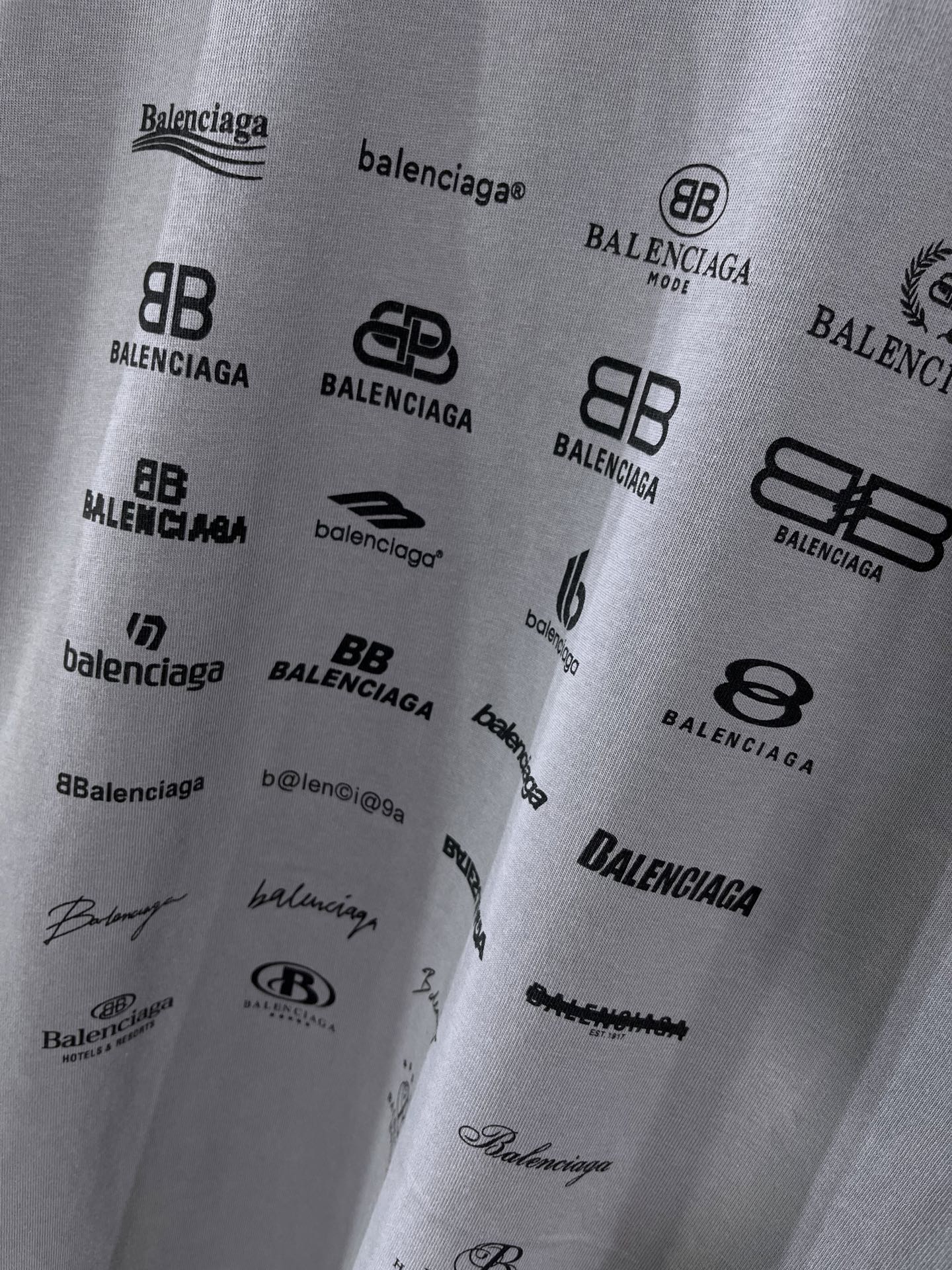 Balenciaga T-shirt fabric close-up showing multiple black logo prints